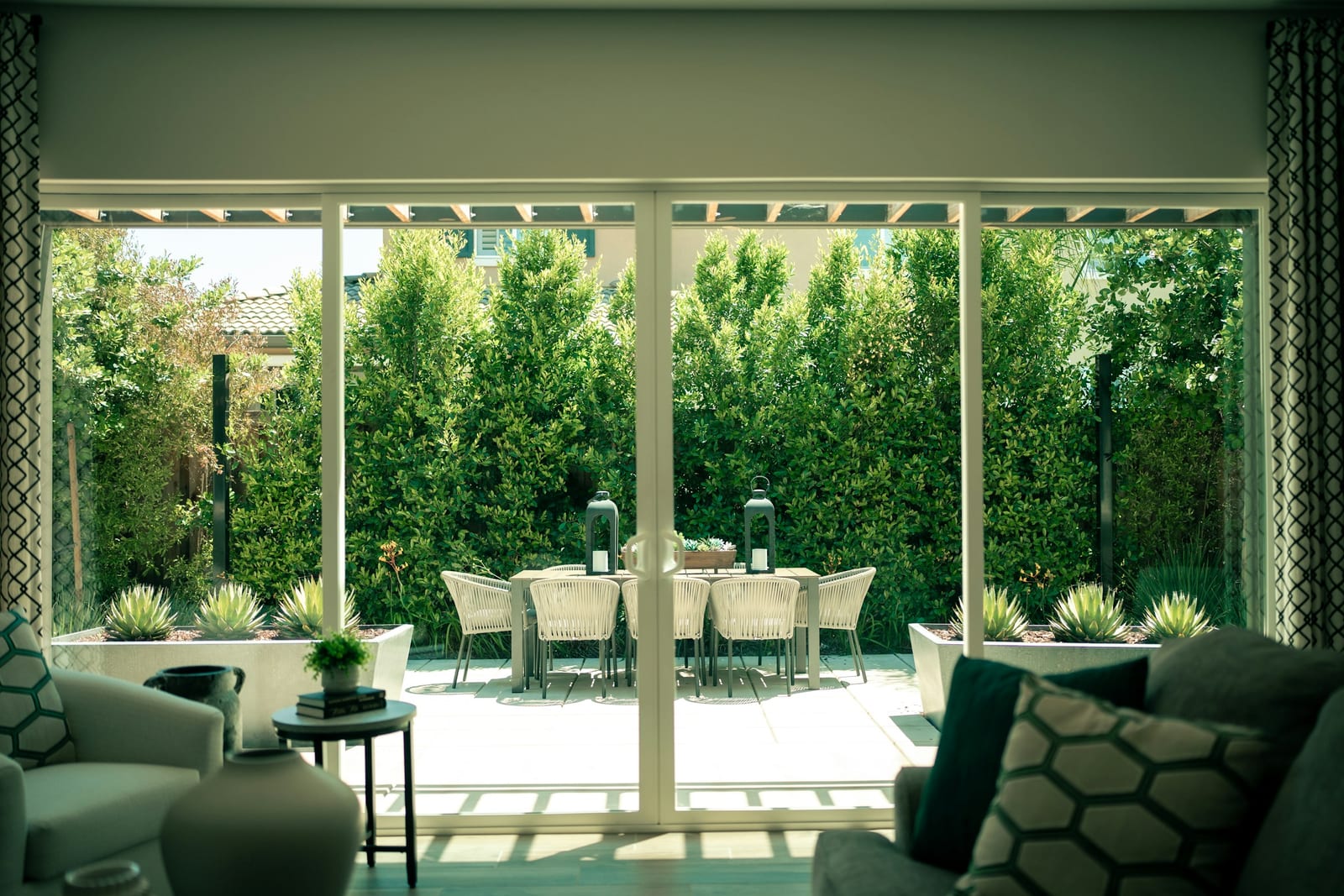 A sliding glass patio door seen from inside a living room, opening onto a planted patio